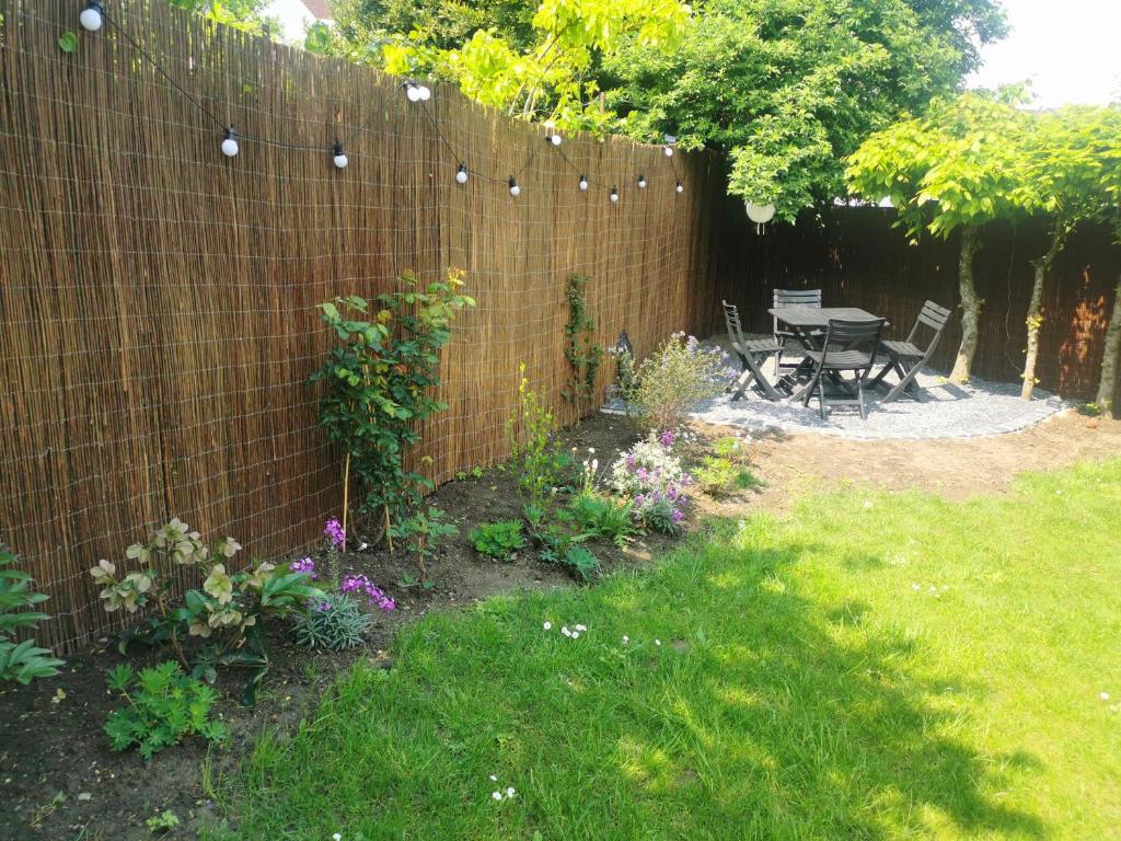 a backyard with a fence and a table and some flowers at Hydrangea Cottage Arras in Saint-Laurent-Blangy