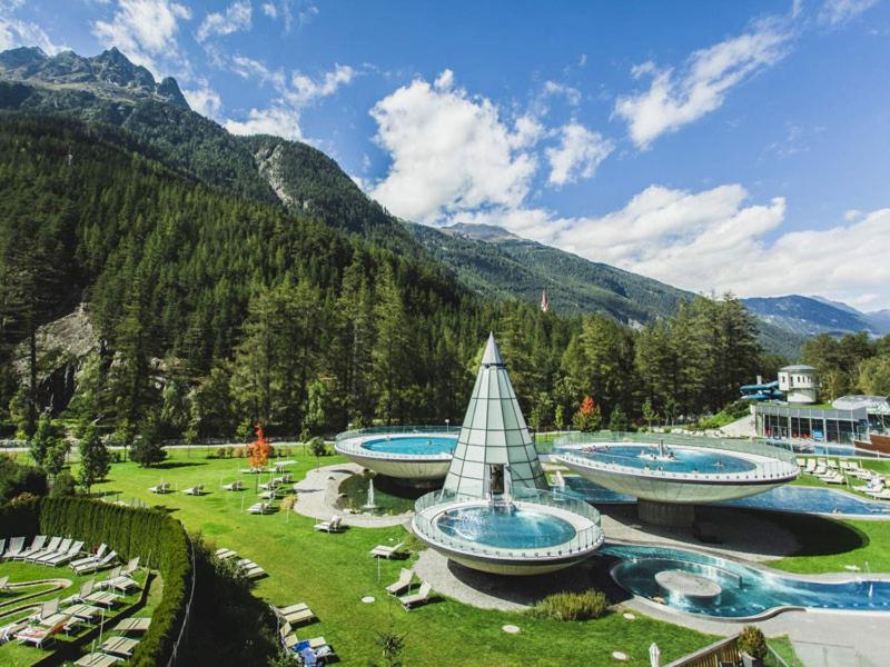 a resort with two swimming pools in the mountains at Pension Alpina in Roppen