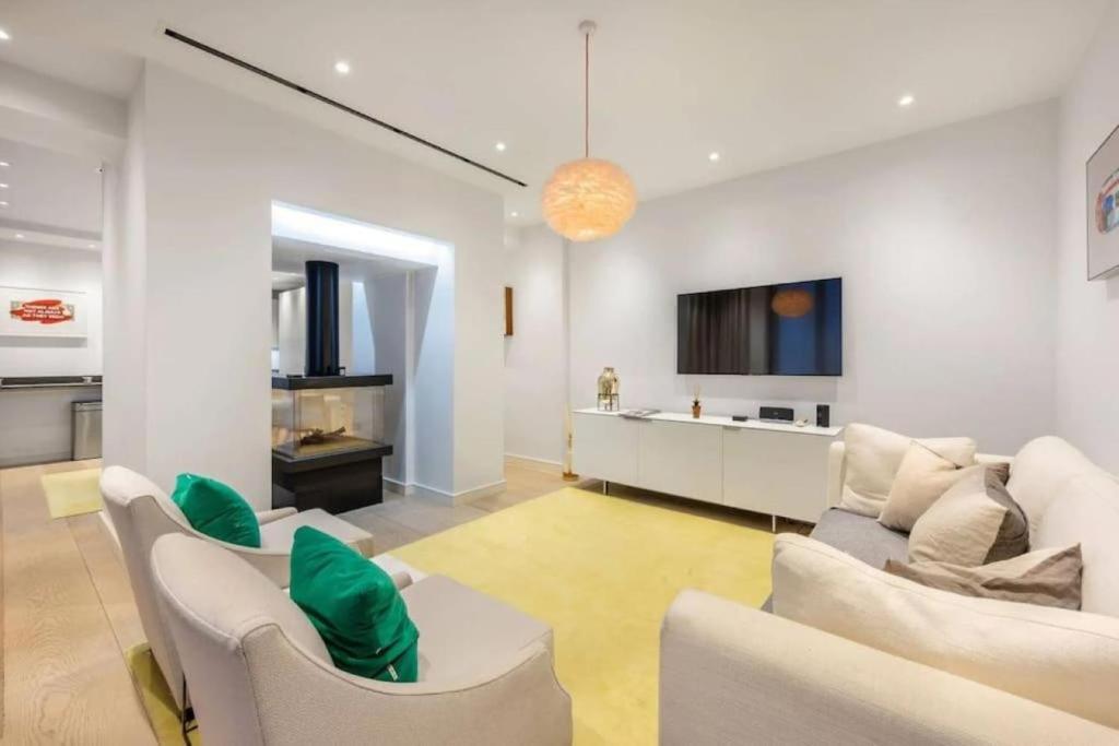 uma sala de estar com mobiliário branco e uma cozinha em Stunning Mayfair 3 bed flat with terrace and fireplace em Londres