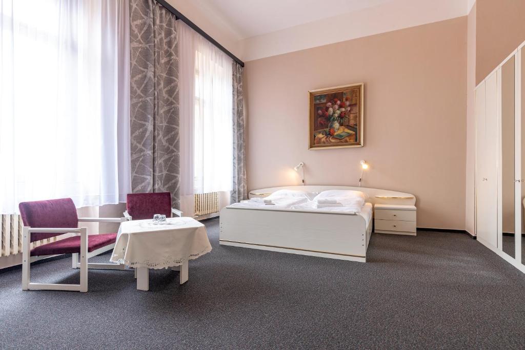 a bedroom with a bed and a table and chairs at Hotel Slovan Plzeň in Pilsen