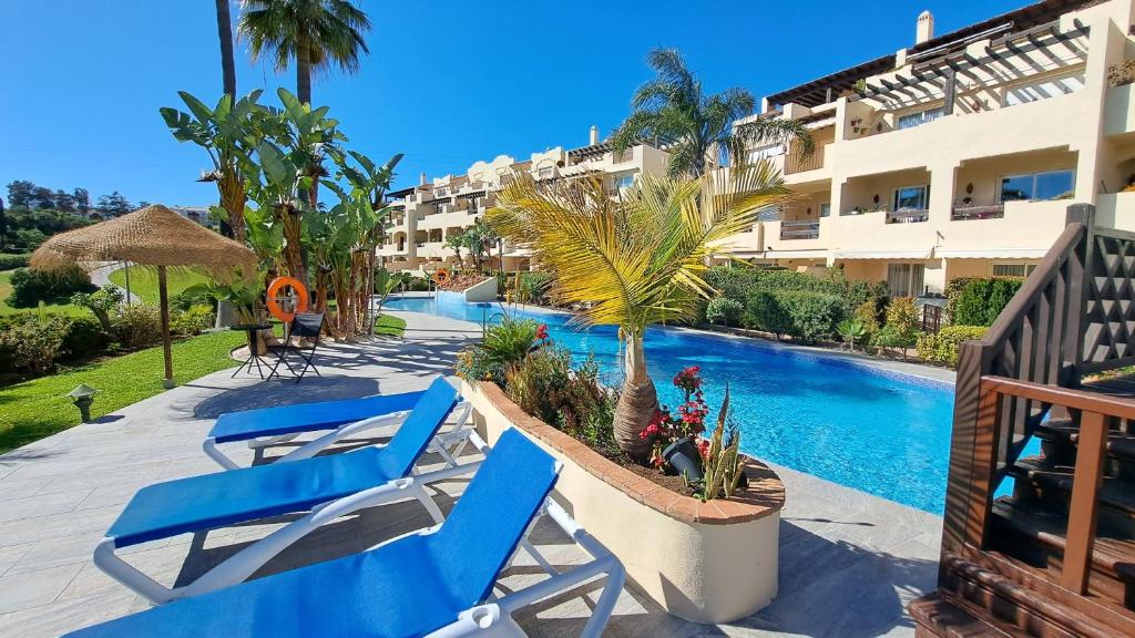 twee blauwe stoelen en een zwembad in een resort bij Sunny holiday Apartment Miraflores in Sitio de Calahonda