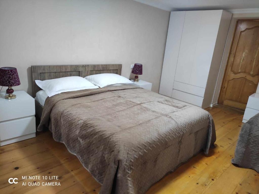 een slaapkamer met een groot bed met 2 nachtkastjes bij Tskaltubo Apartment Meri in Tskaltubo