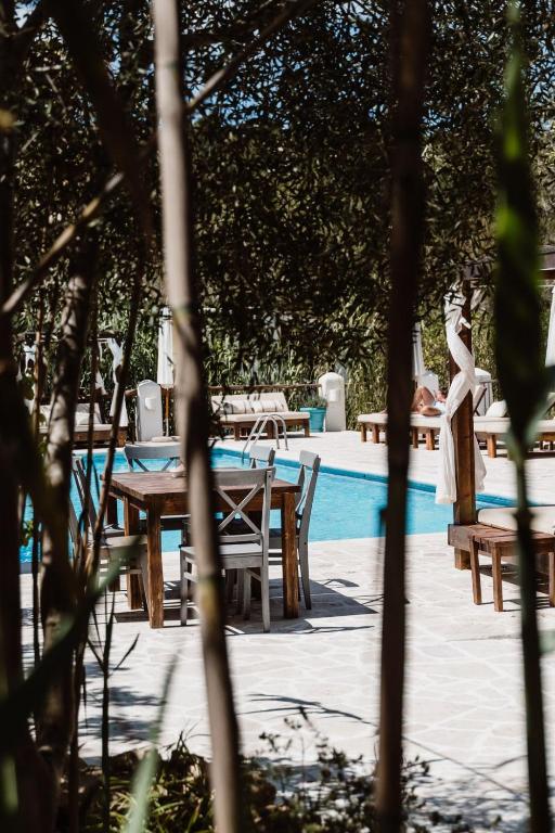 Una mujer parada junto a una mesa y sillas junto a una piscina. en Can Vistabella Boutique Resort, en San Antonio