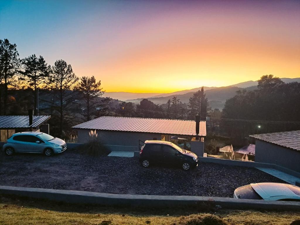 two cars parked in front of a house with the sunset at Tres Vientos - Lofts de Montaña Raco in Raco