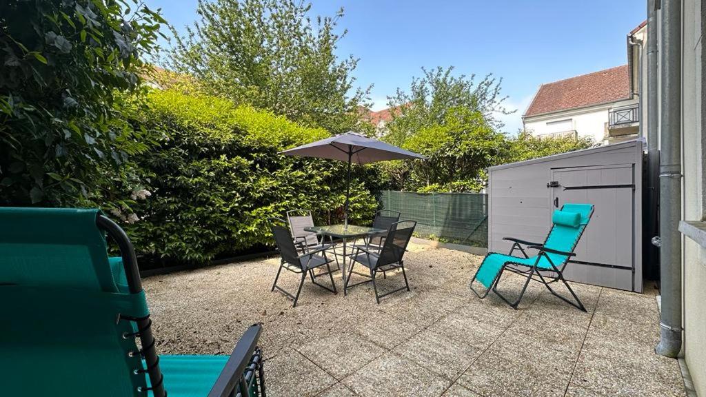 a patio with a table and chairs and an umbrella at Appartement T2 Rez de jardin - Disneyland Paris 6 min in Bussy-Saint-Georges