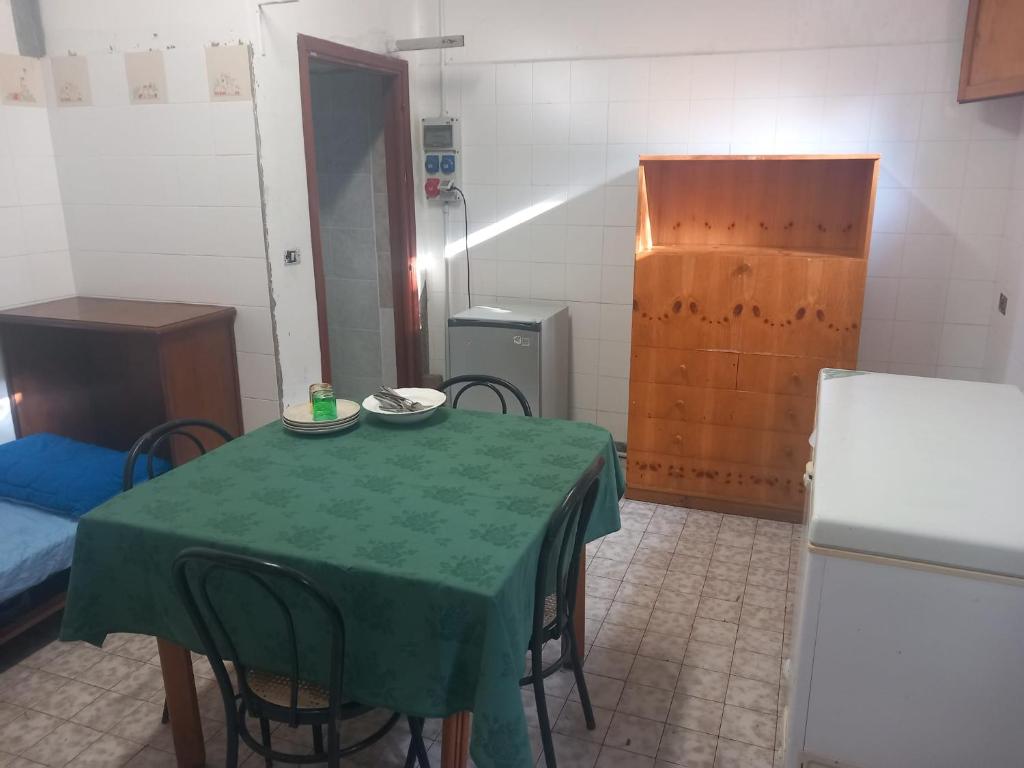 een kamer met een groene tafel met stoelen en een koelkast bij appartamento di Domenico 