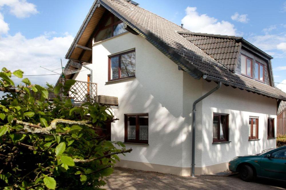 Una casa blanca con un coche aparcado delante. en Ferienwohnung Eifelmond, en Nettersheim