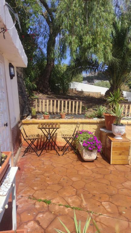 un patio con un banco, una mesa y flores en Casita con mirador, en Málaga