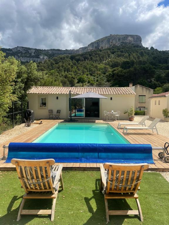 a swimming pool with two chairs and a house at Studio de charme avec piscine in Fontaine-de-Vaucluse