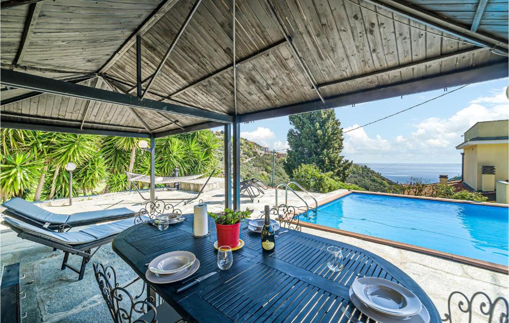 un tavolo blu e sedie su un patio con piscina di Amazing Home In Noli With Private Swimming Pool, Can Be Inside Or Outside a Noli