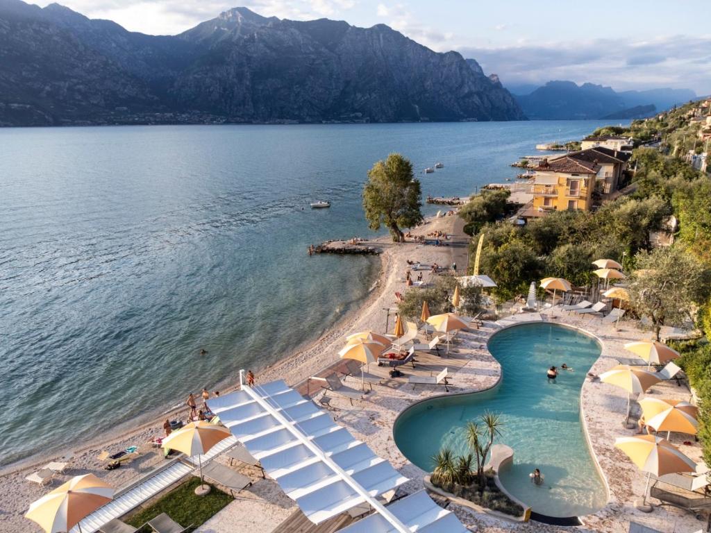 a view of a beach with umbrellas and a swimming pool at Ambienthotel PrimaLuna in Malcesine