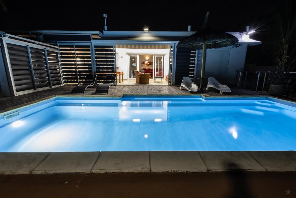 a swimming pool at night with a house in the background at Les Villas 33 Bis in Baie du Tombeau