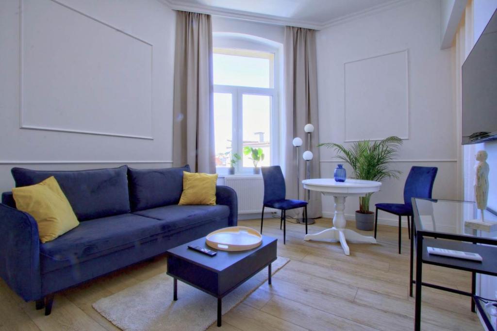 a living room with a blue couch and a table at Ottimo Apartamenty Jagiellońska in Bydgoszcz