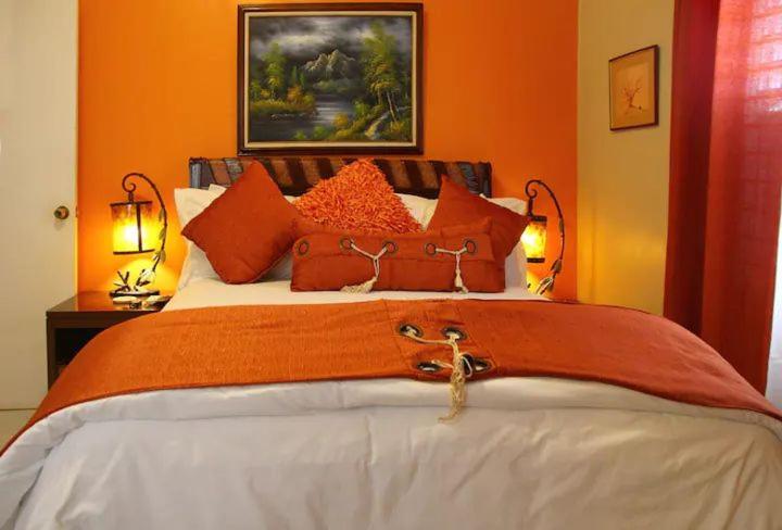 a bedroom with a large bed with orange walls at The Exoria Cottage in Ocho Rios