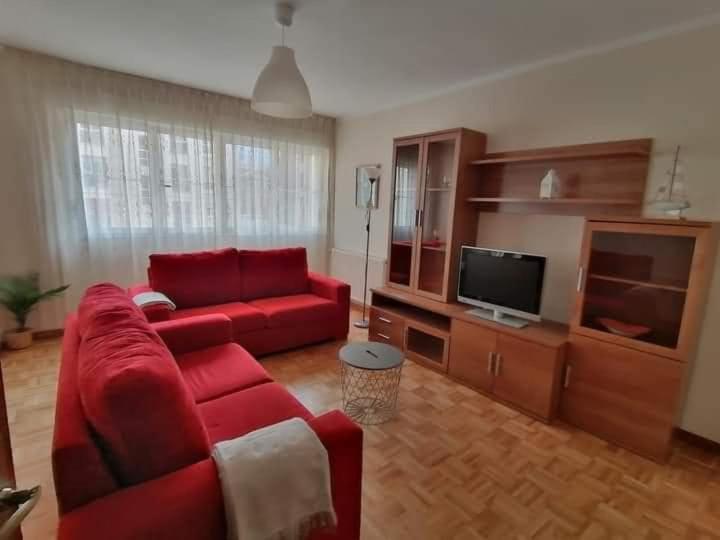 een woonkamer met een rode bank en een flatscreen-tv bij Altamar in Llanes