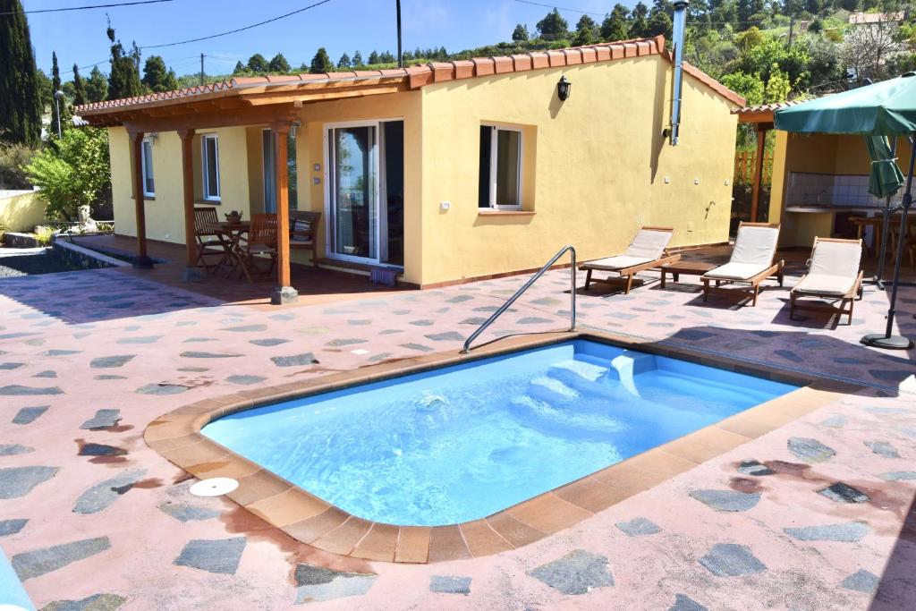 una piscina en un patio con sillas y una casa en Casa Florita en Puntagorda