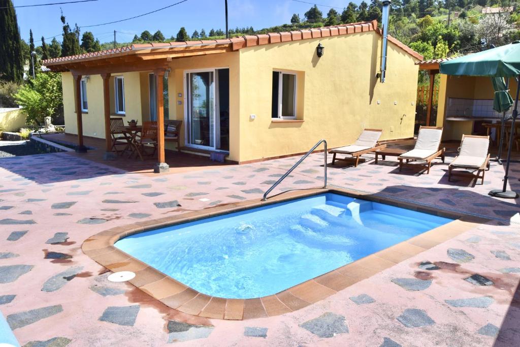 una piscina en un patio con sillas y una casa en Casa Florita, en Puntagorda