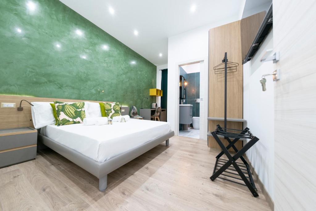 a bedroom with a large white bed and a green wall at Catone Luxury Rooms in Rome
