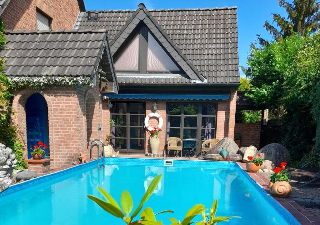 una casa con piscina di fronte a una casa di Ferienwohnung am Niederrhein a Kevelaer