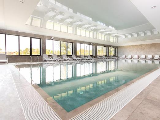 a large swimming pool with chairs in a building at Alexis apartament Dziwnów in Dziwnów