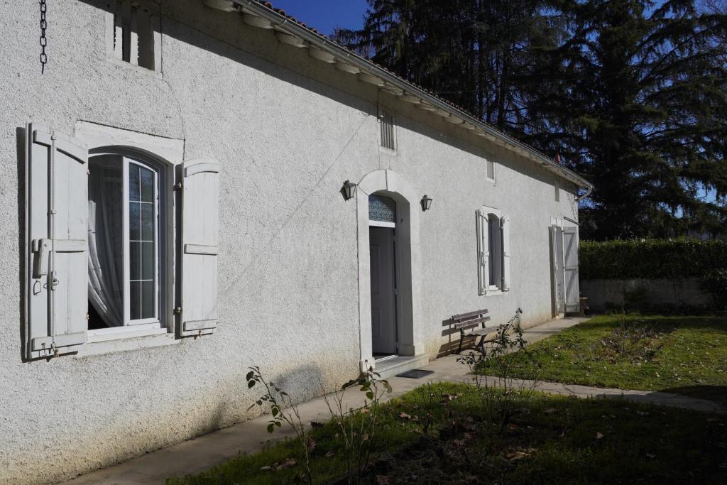 ein weißes Gebäude mit einer Tür und einer Bank daneben. in der Unterkunft Grande maison accueillante 