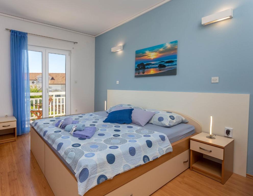 sypialnia z łóżkiem z niebieskimi ścianami i oknem w obiekcie Apartments Ivanović w Hvarze