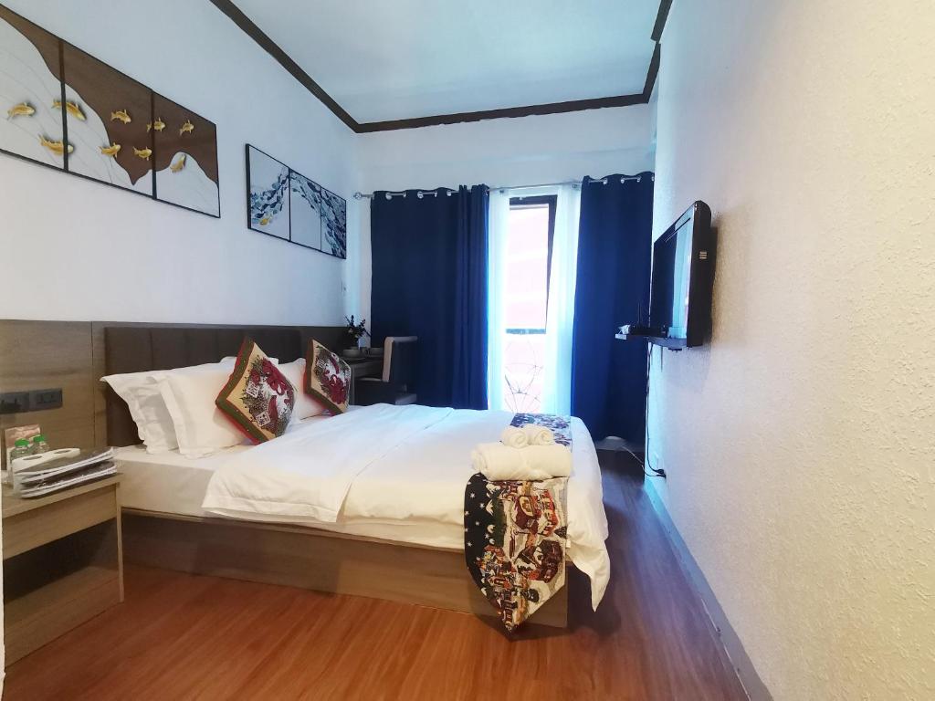 een slaapkamer met een bed met blauwe gordijnen en een televisie bij warm makati in Manilla