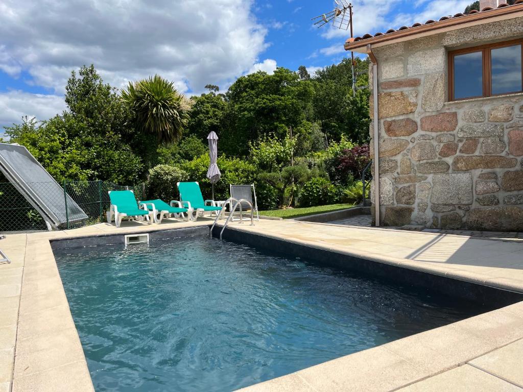 a swimming pool with blue chairs and a house at Casa da Lage - Gerês - Piscina privada in Geres
