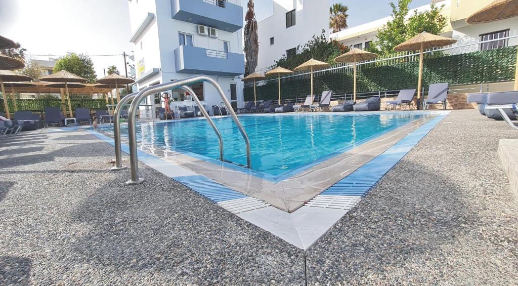 a swimming pool in front of a building at JP Pool & Apartments in Kardamaina