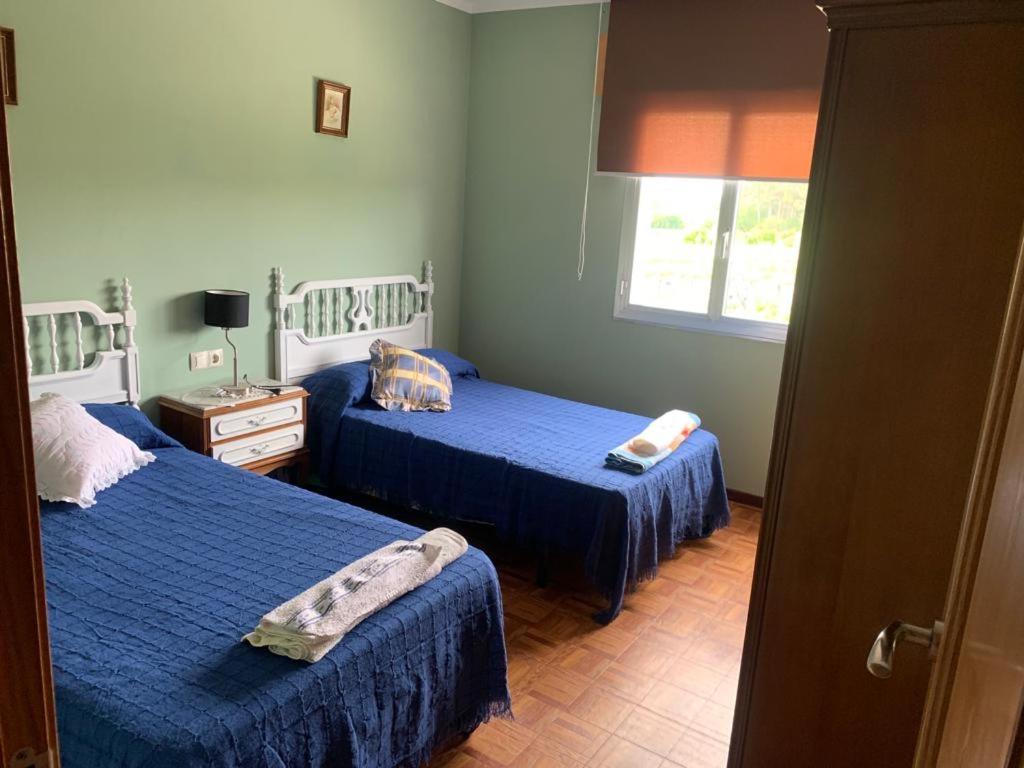um quarto com 2 camas azuis e uma janela em Migueliño - Casa Tía María em Vilanova de Arousa