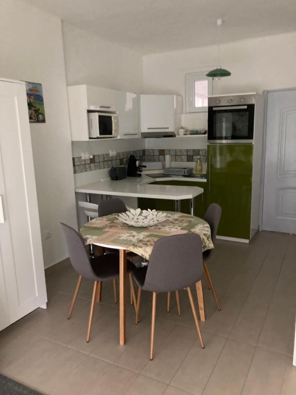 uma cozinha com uma mesa e cadeiras e um frigorífico verde em Éva apartman em Balatonboglár