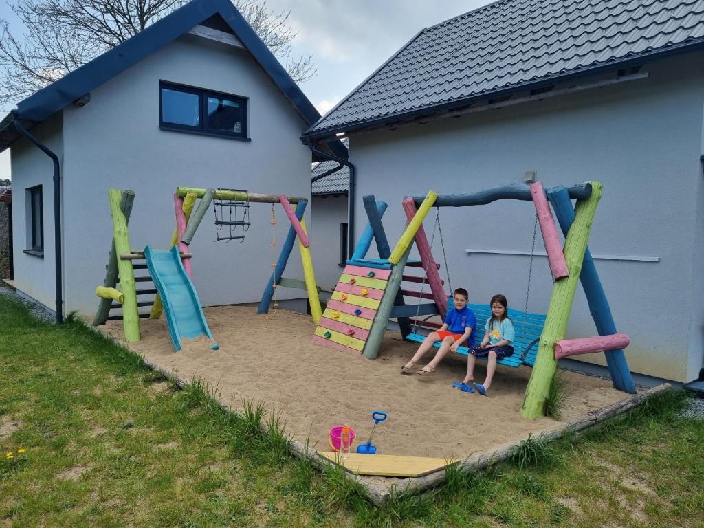 two children sitting on a playground in the sand at Domki na Wzgórzu Jastrzębia Góra Tupadły in Jastrzębia Góra