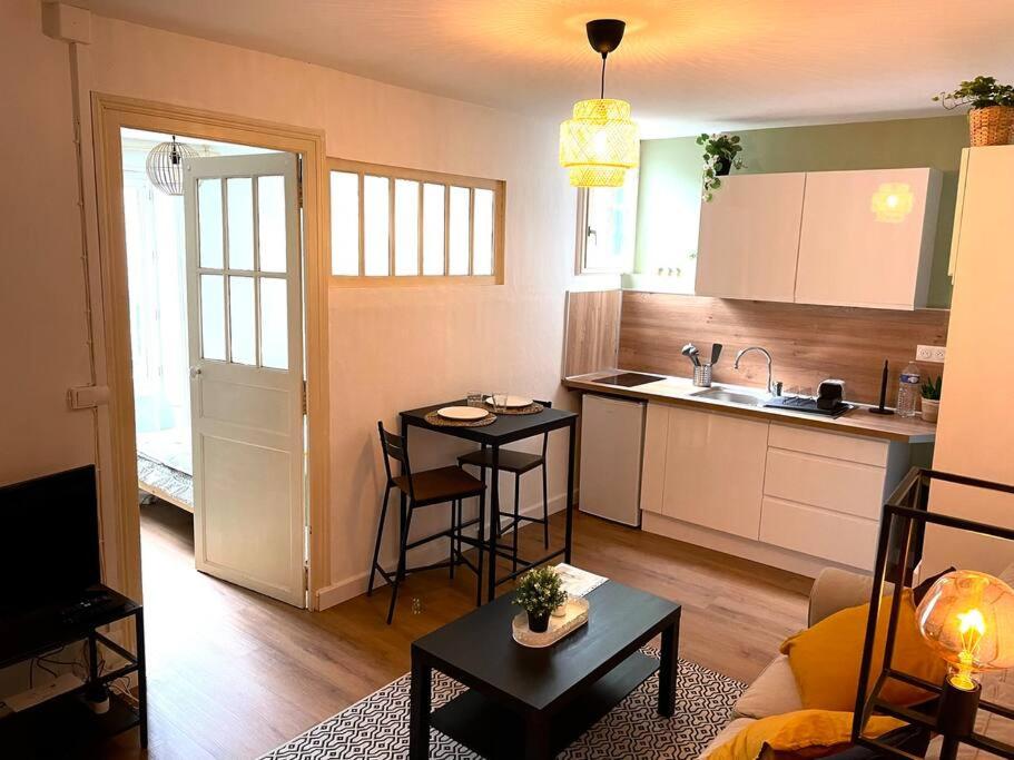 a kitchen and a living room with a table and a kitchen at Appartement calme et cosy in Pau