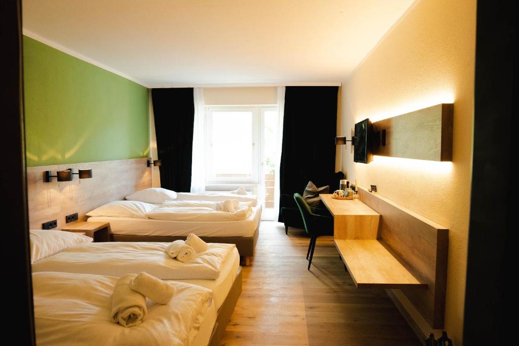 ein Hotelzimmer mit 3 Betten und einer grünen Wand in der Unterkunft Ahorn Hotel in München