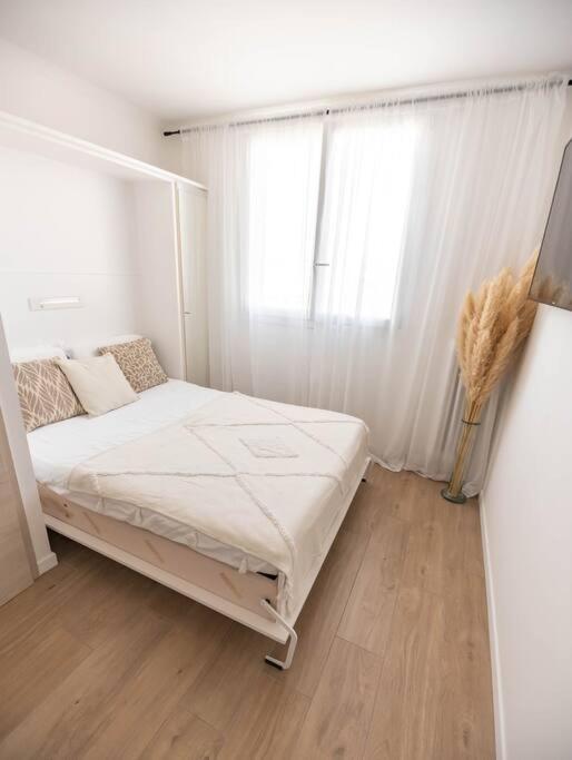 une chambre blanche avec un lit et une fenêtre dans l'établissement Studio / 15min de la plage, à Fréjus