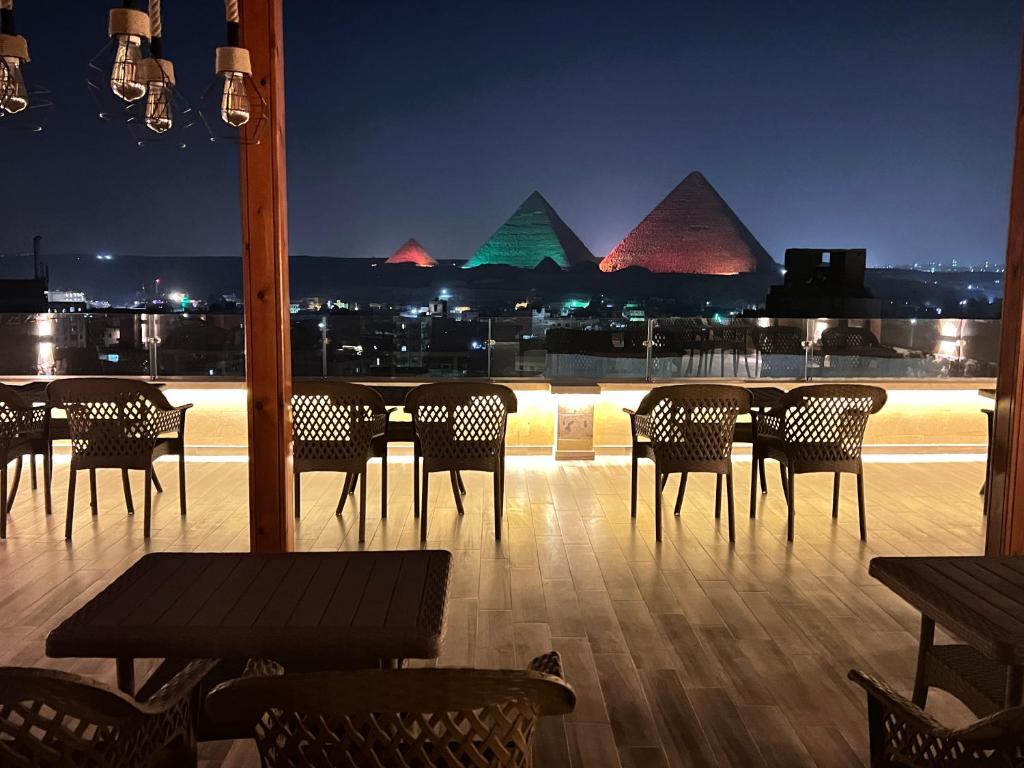 a restaurant with chairs and tables and pyramids at night at Celia Pyramids View inn in Cairo