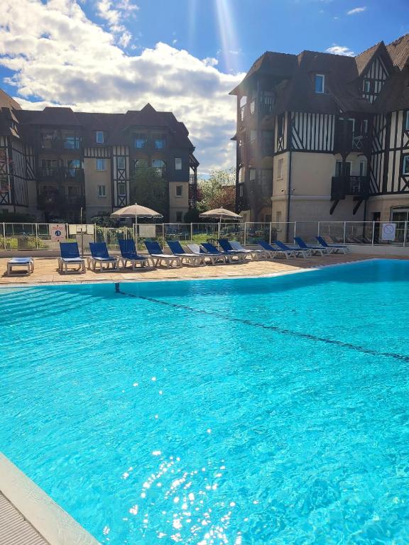 a large swimming pool with blue chairs and buildings at Magnifique appartement 2 pièces in Deauville