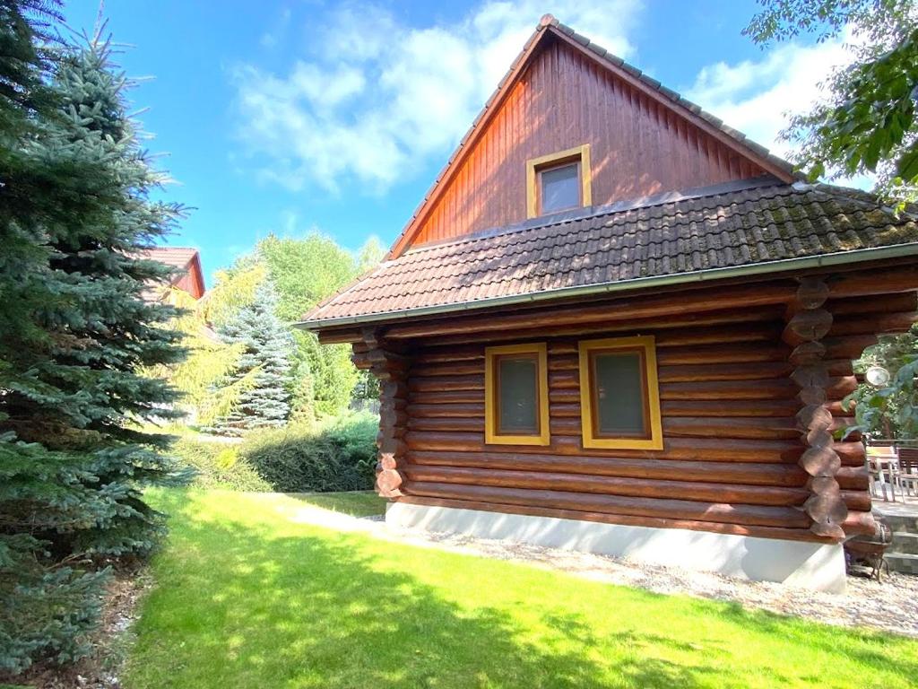 eine Blockhütte im Gras mit einem Baum in der Unterkunft Zrub Kaška in Čadca