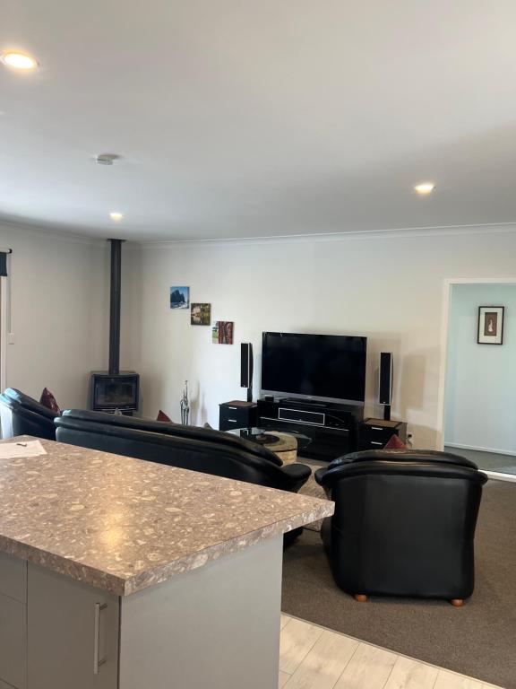a living room with couches and a table and a television at A Cut Above Lodge - The Gateway to the Bay of Islands in Kerikeri