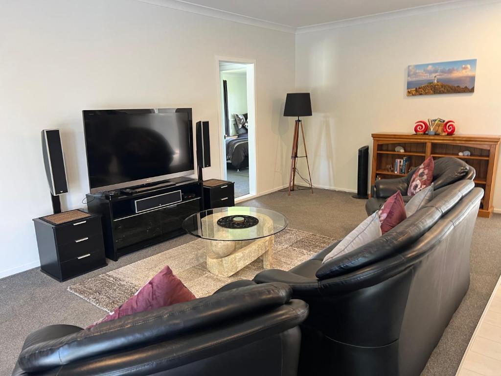 a living room with a couch and a flat screen tv at A Cut Above Lodge - The Gateway to the Bay of Islands in Kerikeri