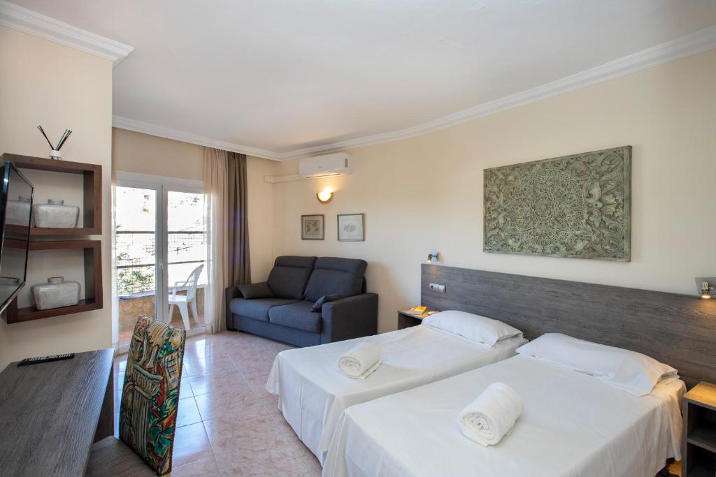 プラヤ・デアロにあるHabitacions Villa Cristinaのベッド2台とソファが備わるホテルルームです。