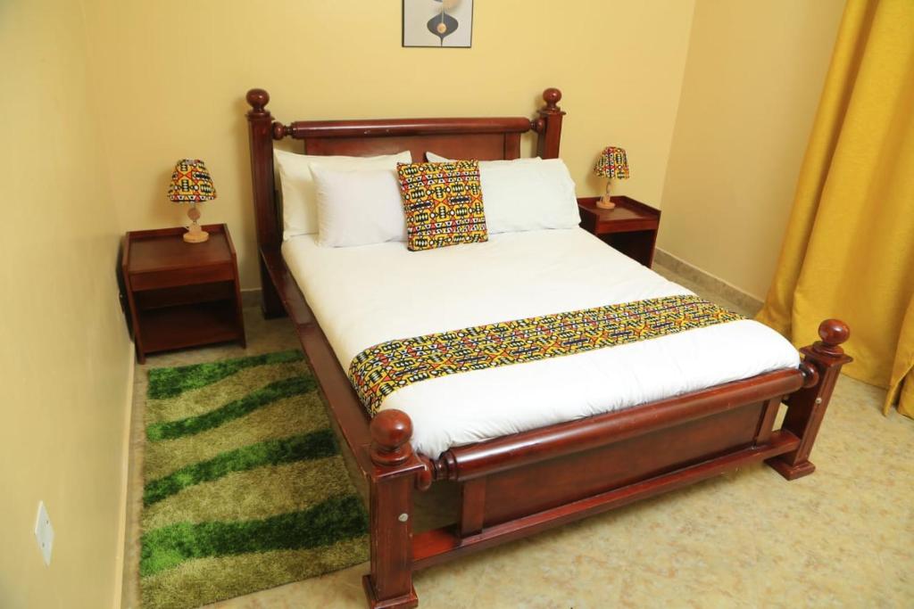 ein Bett in einem Schlafzimmer mit zwei Nachttischen und zwei Lampen in der Unterkunft Palm Star Motel in Fort Portal