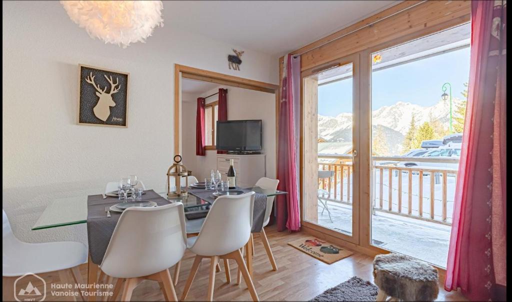 ein Esszimmer mit einem Tisch und Stühlen sowie einem Balkon in der Unterkunft Au Centre de la station de ski de Valfréjus - appartement 4-6 personnes in Valfréjus