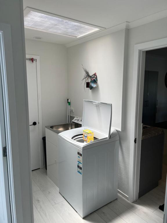 a white kitchen with a sink and a mirror at A Cut Above Lodge - The Gateway to the Bay of Islands in Kerikeri