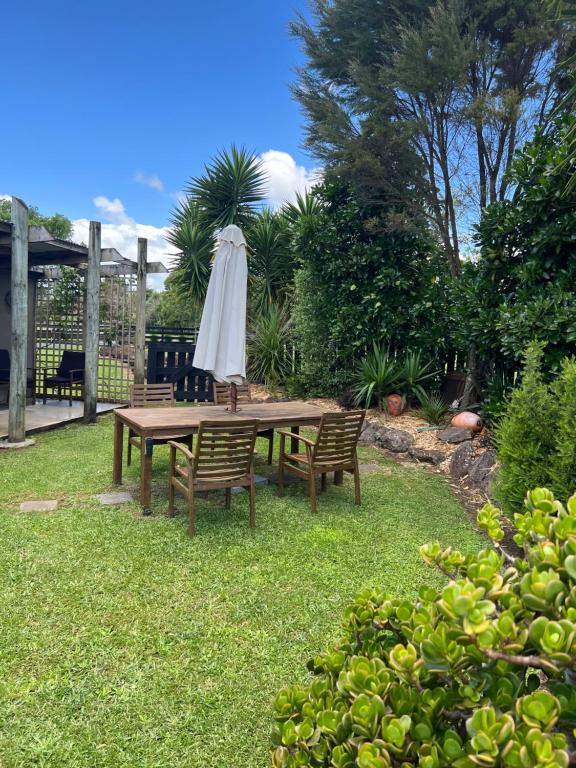 a picnic table with an umbrella and two chairs at A Cut Above Lodge - The Gateway to the Bay of Islands in Kerikeri