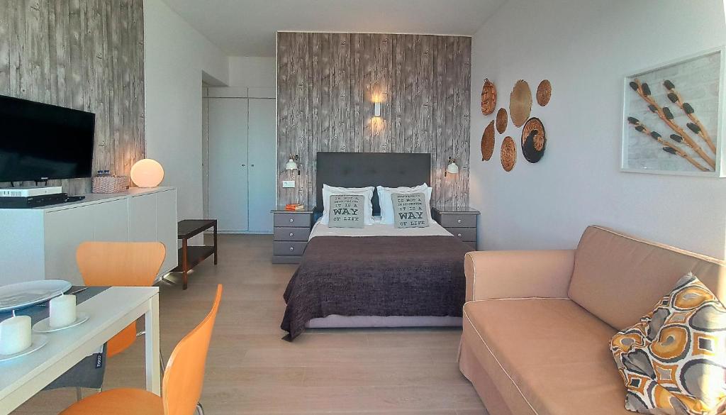 a bedroom with a bed and a couch and a tv at Apart Great Sea View in Alvor