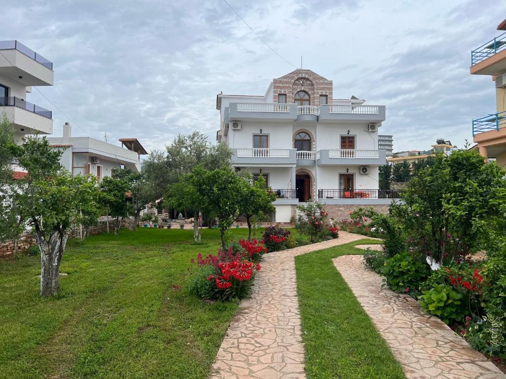 ein großes weißes Haus mit einem Garten davor in der Unterkunft Vila Sidi in Ksamil