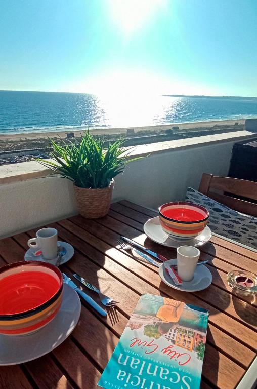 a table with plates and cups on a balcony with the ocean at Apart Great Sea View in Alvor