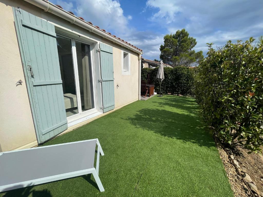 a garden with a bench on the grass at Superbe appartement 6pers avec piscine et jardin in Fréjus