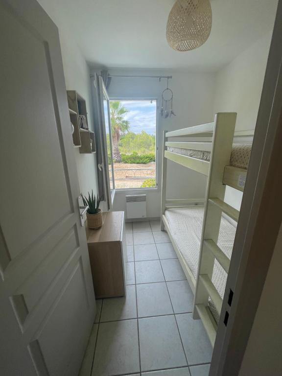 a small room with a bunk bed and a window at Superbe appartement 6pers avec piscine et jardin in Fréjus